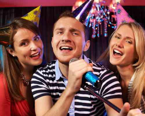 Rocking Out at 50 With Karaoke. Group of Friends Singing Karaoke at a 50th Birthday Party.