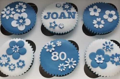 Personalized cupcakes for a milestone 80th birthday. Cupcakes decorated with blue and white flowers.