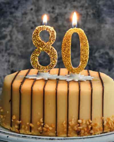 Happy 80th Birthday Cake: Celebrate 80 Years Beautiful 80th birthday cake topped with lit glittery gold candles.