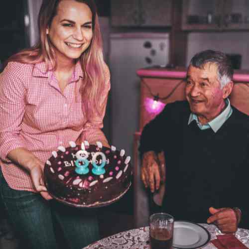 Special milestone celebration! A smile lights up a man's face as he's presented his 80th birthday cake.