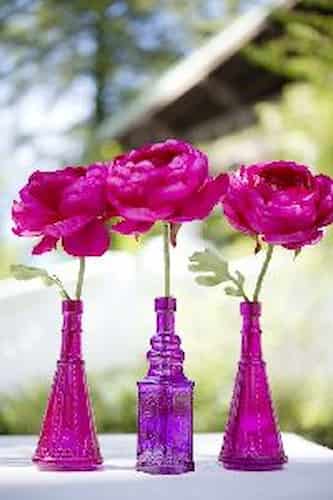 Try this colorful welcome. Three hot pink vases holding hot pink flowers.