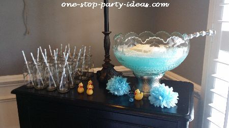 Indulge in the best Punches For Baby Shower:  Try it Now! Milk bottles with straws, yellow rubber ducks, blue pompoms, and punch for baby shower.