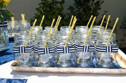Add a Homely Feel to the Punch with Mason Jars. Display of Mason Jars Adorned with Ribbons and Straws.