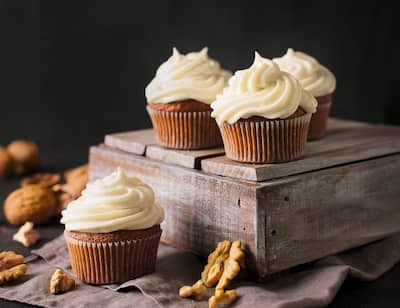 White frosted vanilla cupcakes presented on a rustic riser.