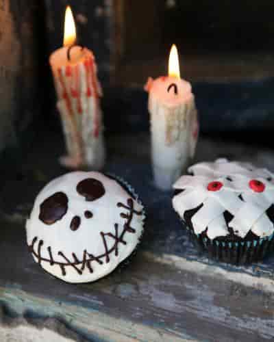 Halloween Mummy Cupcakes Two Ways Two Halloween mummy cupcakes, one with white bandage-like fondant, the other with an eerie smile.