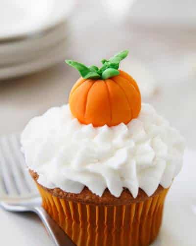 Decorate Halloween Cupcakes with Piped White Icing and a Pumpkin on Top - Elegant and Easy Halloween cupcake decorated with piped white icing and topped with a small edible pumpkin.