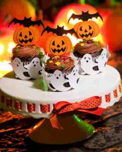 Creative Halloween Cupcake Ideas That Make The Presentation Count Creative Halloween cupcakes displayed on a cake plate with a coordinating ribbon intertwined.