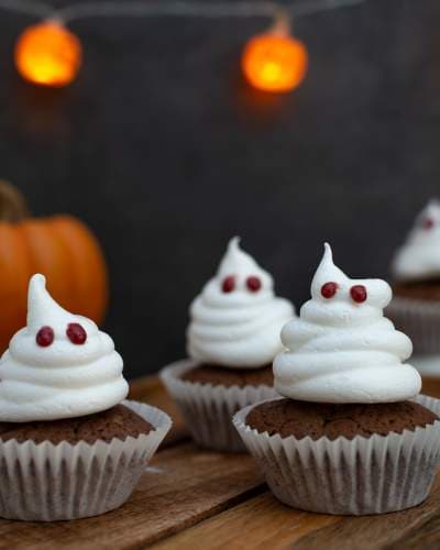 Ghost Halloween Cupcakes - Spooky and Adorable Treats A trio of ghost themed Halloween cupcakes with white frosting shaped like ghosts and eyes.