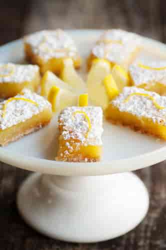 Lemon squares displayed on a white pedestal stand.