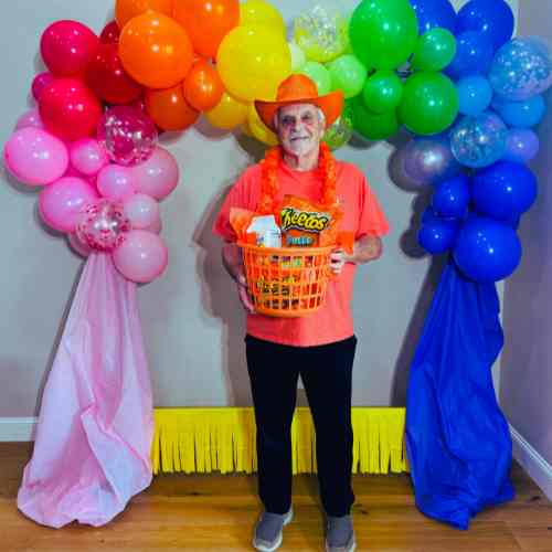 Orange Color Party Ideas: Squeeze The Moment And Make It Orange Orange color party ideas that show a man dressed in orange holding a basket of orange snacks.