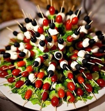 Many colorful vegetables arranged on wooden kabob sticks stuck in a styrofoam ball.